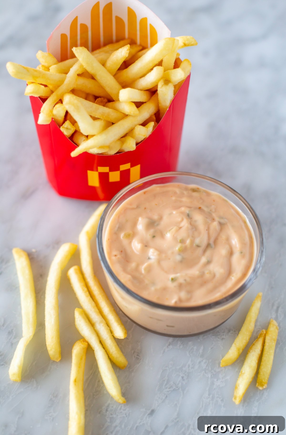 Your 3-Ingredient Big Mac Sauce Secret 8 Overhead shot of homemade Big Mac sauce in a small bowl, next to crispy French fries on a rustic wooden surface.