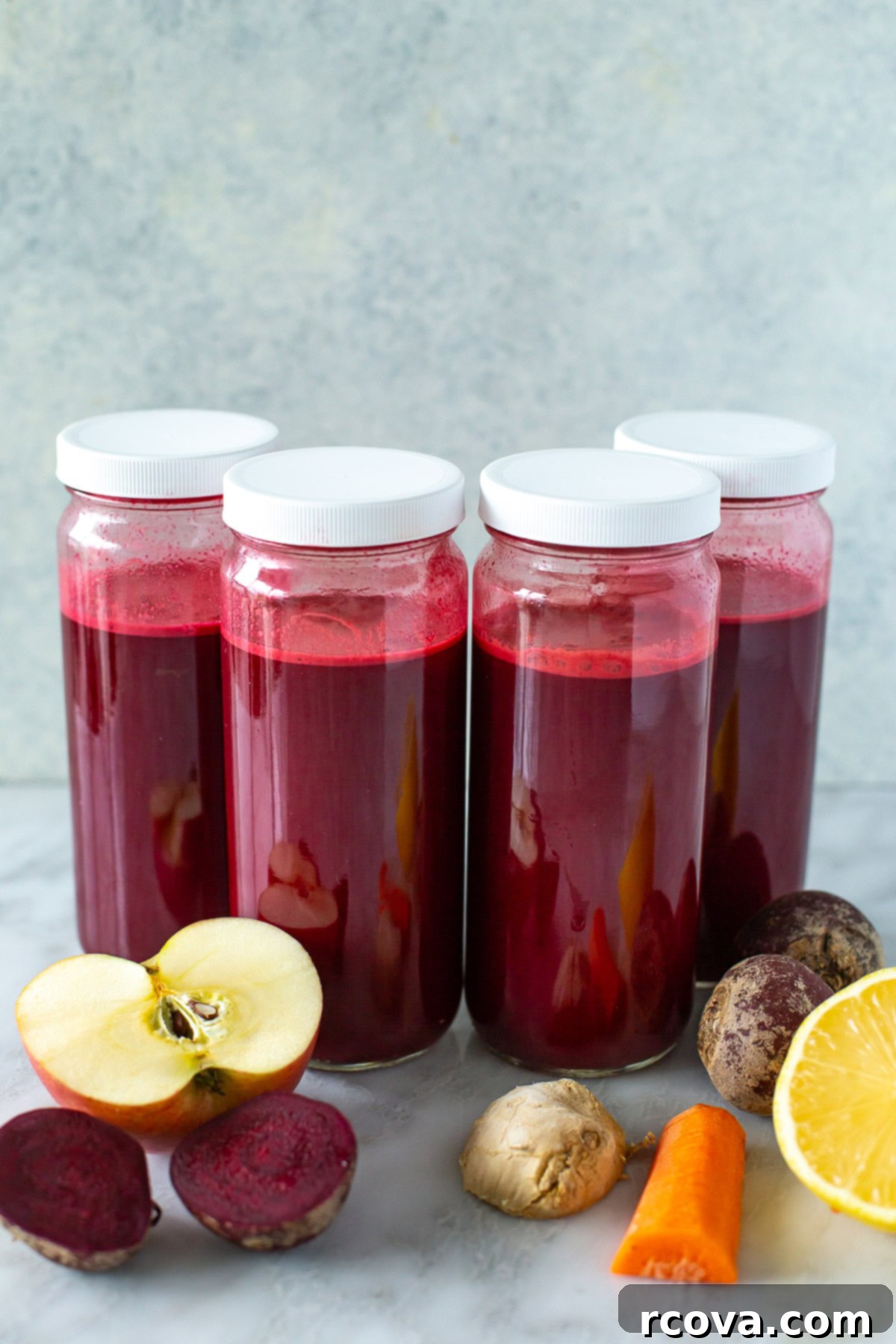 Effortless Homemade Beet Juice 2 side shot of four jars of beet juice with white lids.