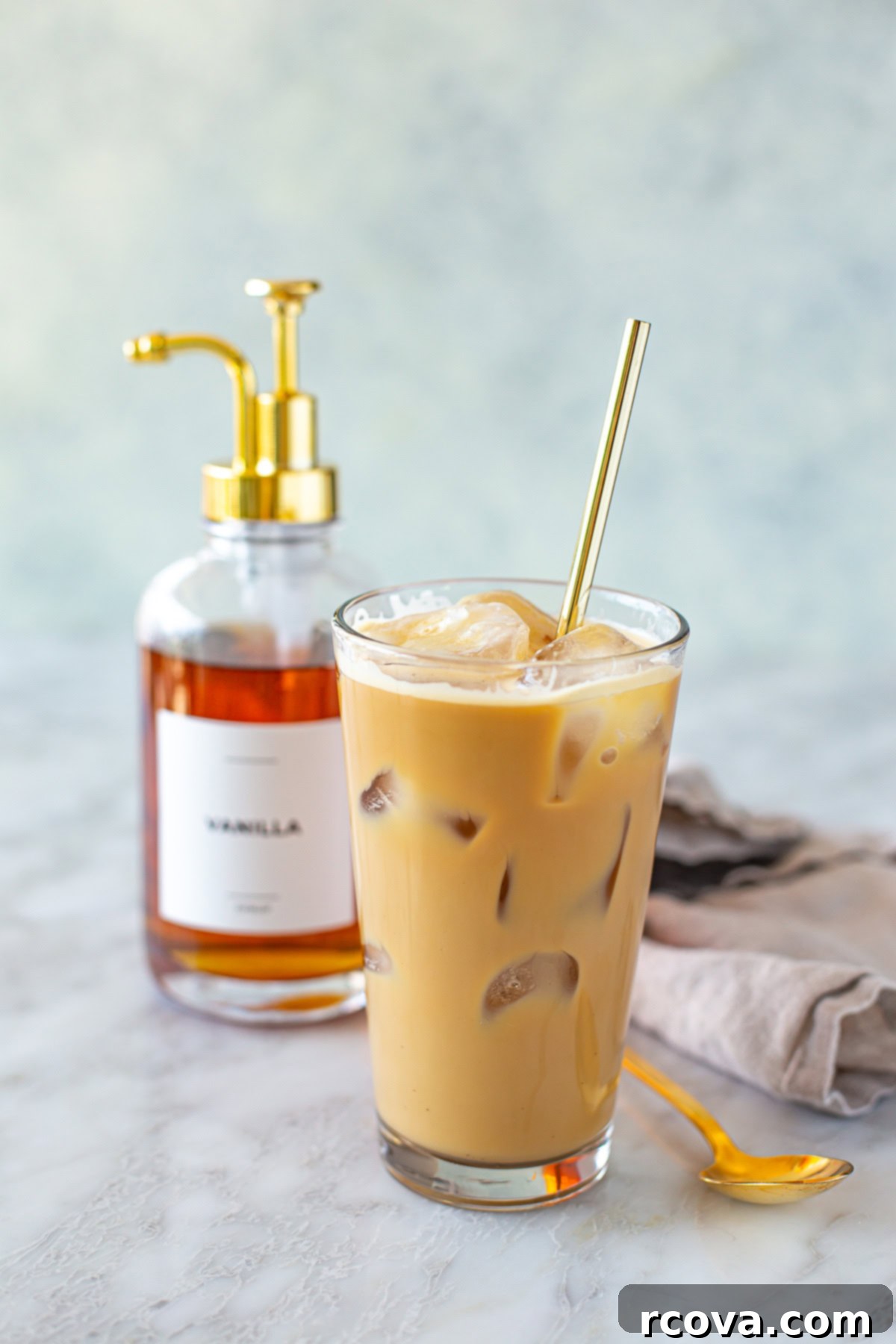Easy Homemade Vanilla Syrup for Iced Coffee 7 Side shot of homemade iced coffee with a vanilla syrup pump visible in the background, showing the perfect pairing.