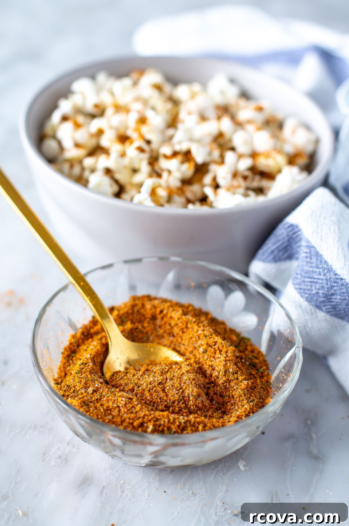Trader Joe Inspired Elote Seasoning 7 Close-up side view of a shaker filled with vibrant Elote seasoning, with a bowl of seasoned popcorn in the background.