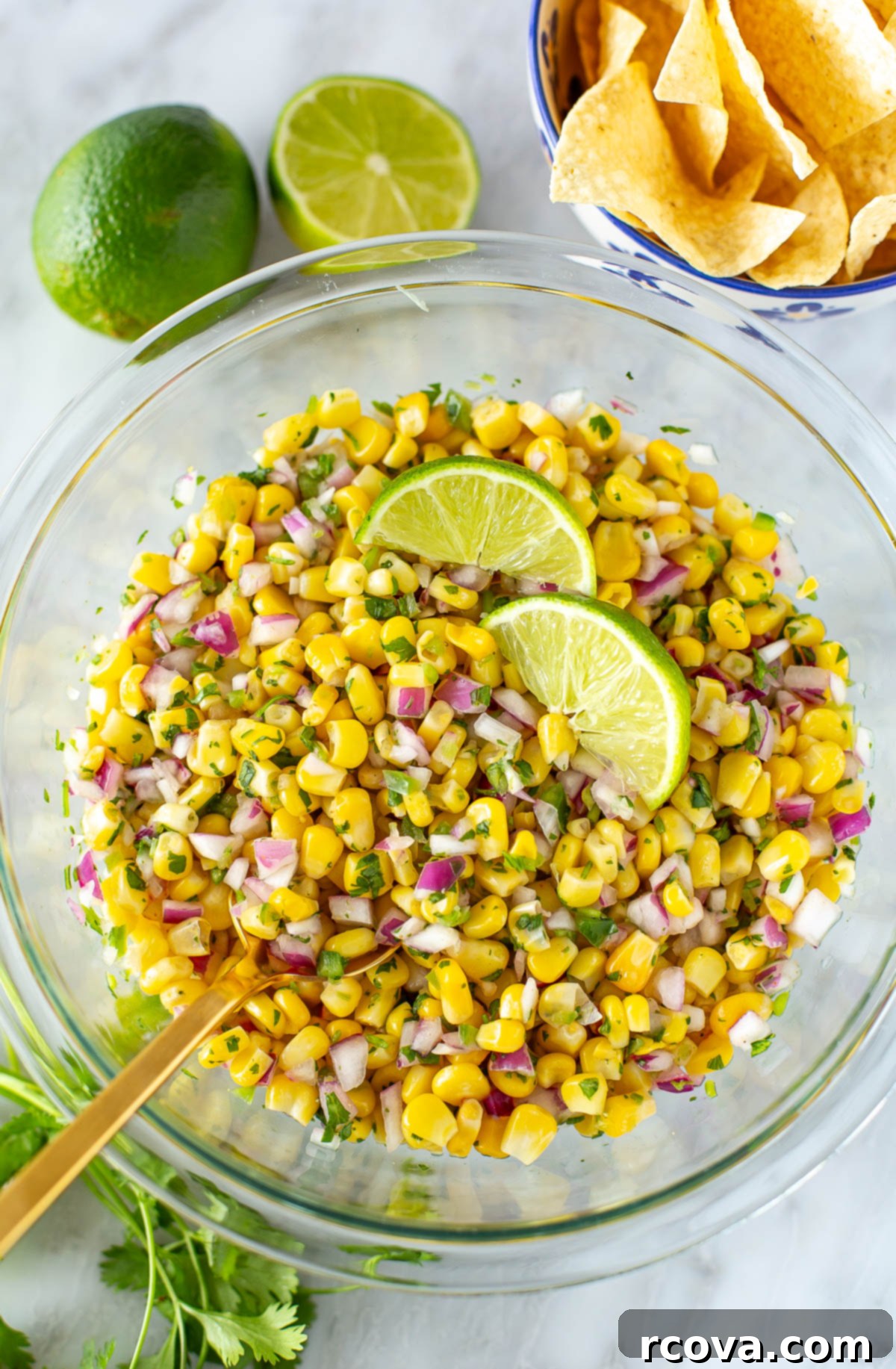Easy Restaurant-Style Chipotle Corn Salsa 7 Overhead shot of the Chipotle-style corn salsa in a white bowl, with a serving spoon, ready for guests.
