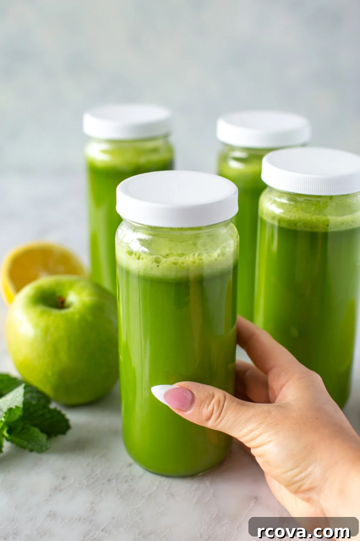 Your Quick Green Elixir 8 Side shot of a hand holding a single glass of vibrant green juice, with other glasses and fresh fruits blurred in the background, creating a dynamic, inviting scene.