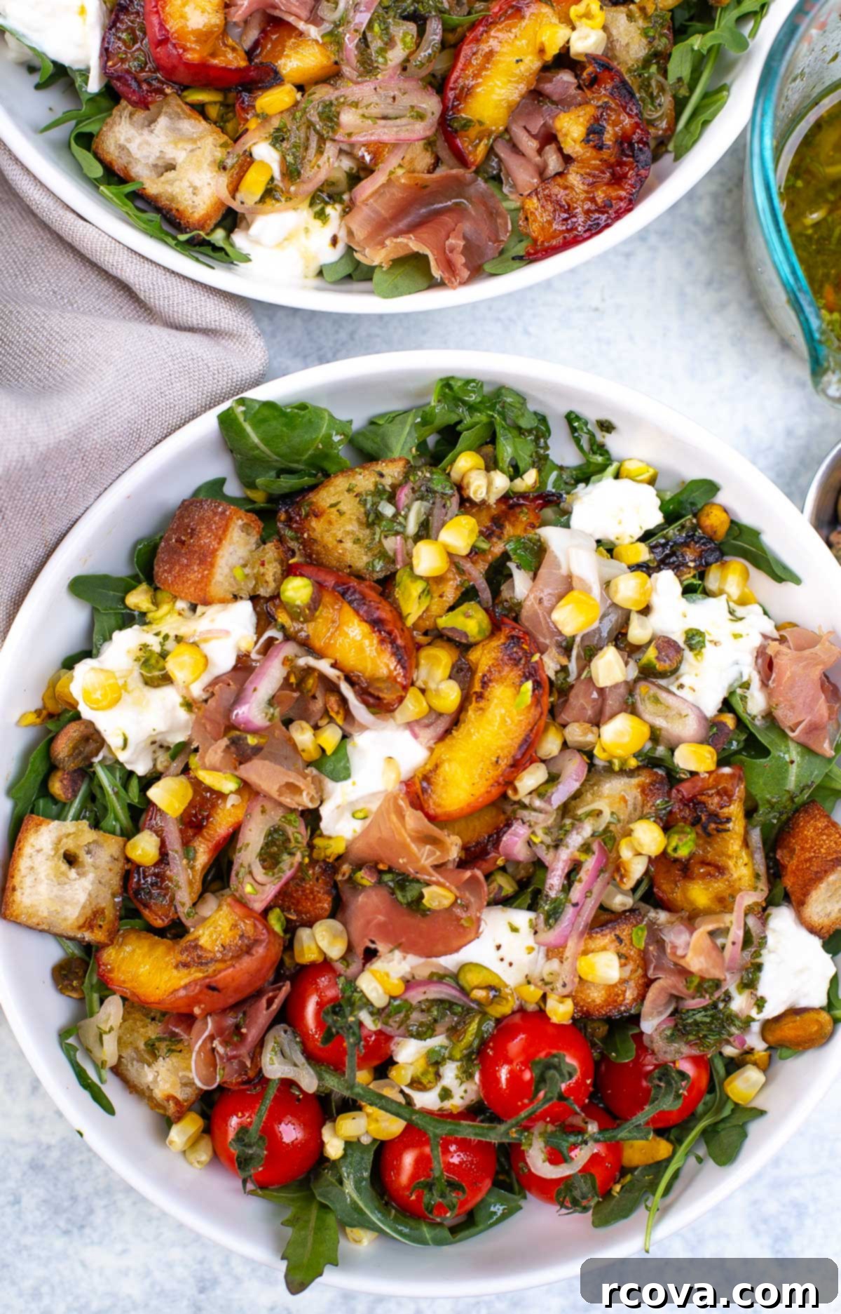 Grilled Peach and Burrata Delight 2 Overhead shot of two bowls of grilled peach burrata salad with various toppings.