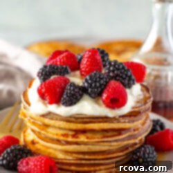 Protein-Packed Greek Yogurt Pancakes 10 Side shot of a tall stack of Greek yogurt pancakes with berries and cream.