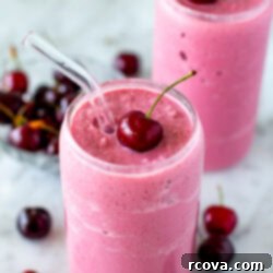 Blissful Cherry Smoothie 8 Side shot of a cherry smoothie with a fresh cherry on top and a straw.