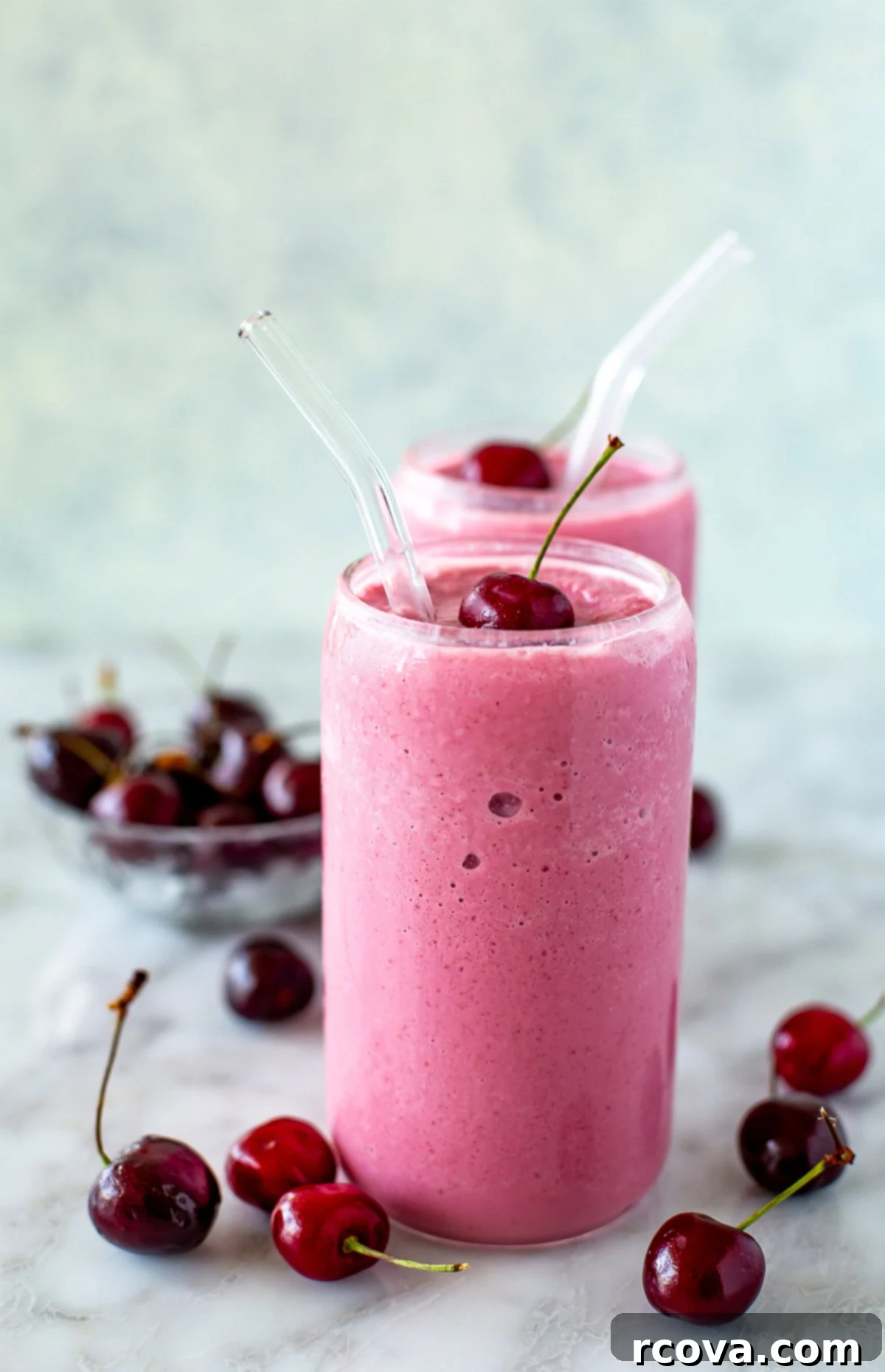 Blissful Cherry Smoothie 6 Two vibrant cherry smoothies, garnished with fresh cherries and straws, displayed beautifully.
