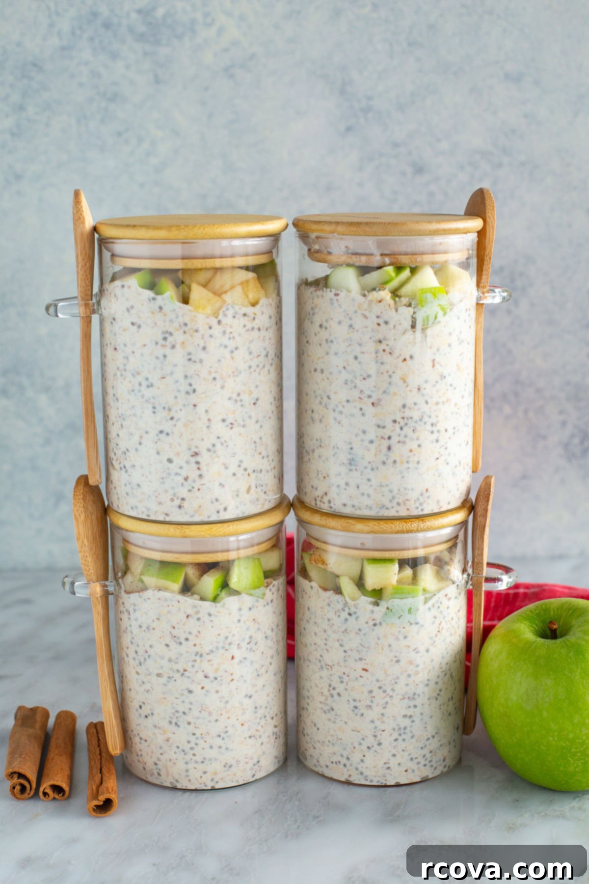 Cozy Apple Cinnamon Overnight Oats 8 A visually appealing side shot of four glass jars of Apple Cinnamon Overnight Oats, neatly stacked, showcasing the layers of oats and apples.