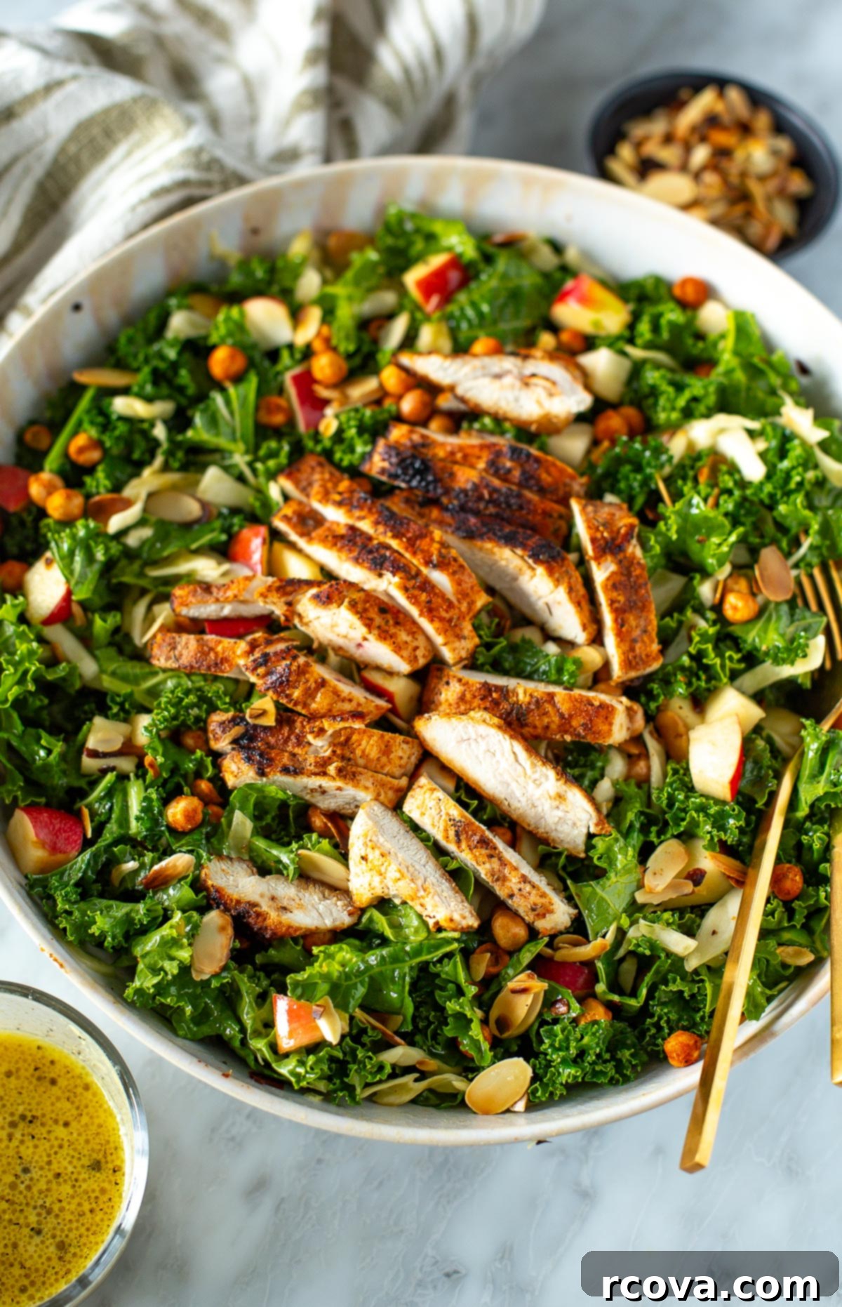 Ultimate Kale Crunch Salad 8 Overhead shot of a beautifully assembled bowl of kale crunch salad with chicken, a fork ready to dig in, and a small cup of dressing on the side.