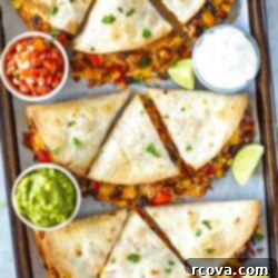 One-Pan Quesadilla Perfection 11 Overhead shot of a sheet pan full of finished quesadillas with side bowls of guacamole and salsa.
