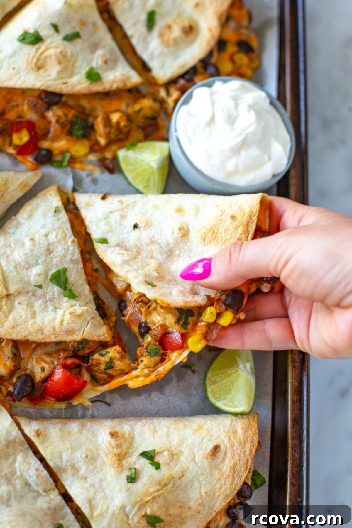 One-Pan Quesadilla Perfection 8 Overhead shot of a hand picking up a slice of a sheet pan quesadilla.
