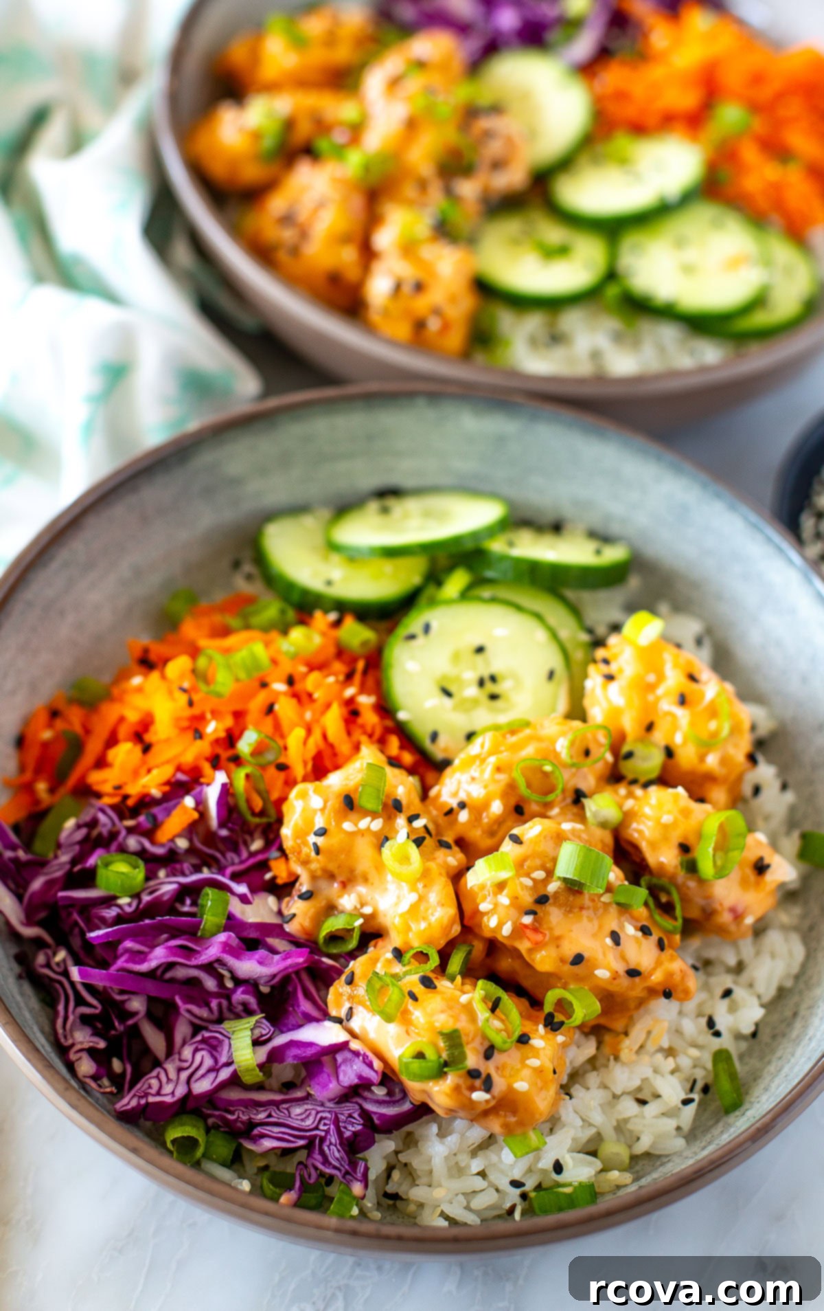 Szechuan Peanut Punch 2 Two vibrant bowls of homemade Bang Bang Chicken served with fresh vegetables and a creamy, spicy-sweet sauce, ready to be enjoyed.