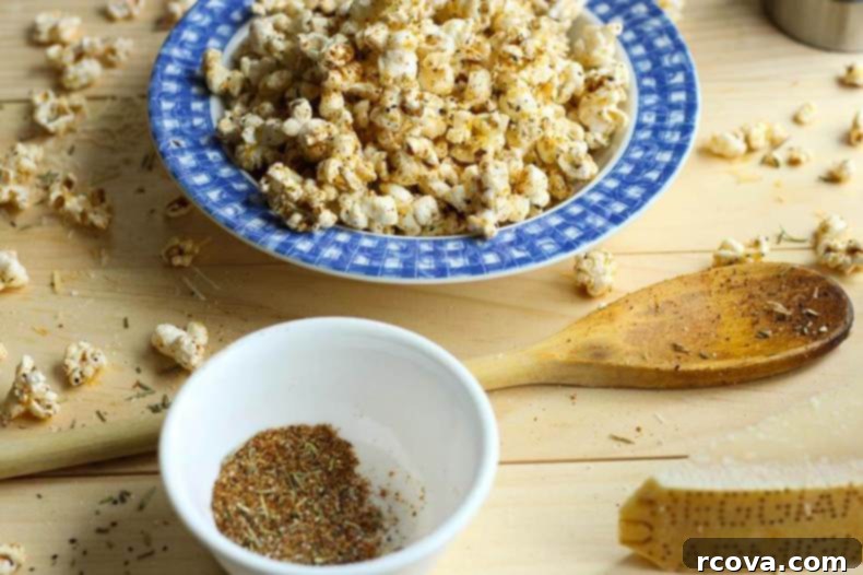 Simple Garlic Parmesan Popcorn 9 Easy Spicy Garlic Parmesan Popcorn in a rustic wooden bowl with herbs and garlic cloves around it.